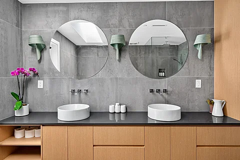 Double vanity bathroom with grey tile and wood cabinetry at 262 West 19th Ave