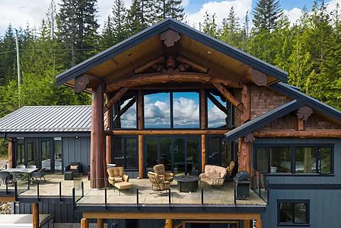 Post-and-beam timber lodge exterior surrounded by forest