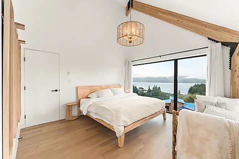 Bright bedroom with a vaulted ceiling and panoramic ocean and mountain views