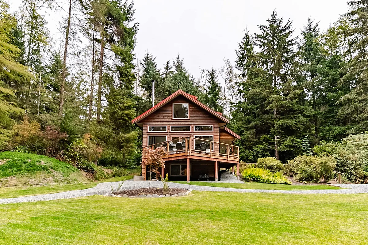 Cedar cabin and lawn surrounded by forest