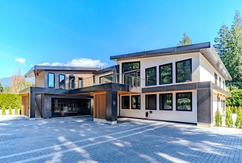 Modern West Vancouver custom home exterior photographed at golden hour with Coastal Mountain backdrop — architectural real estate photography Vancouver