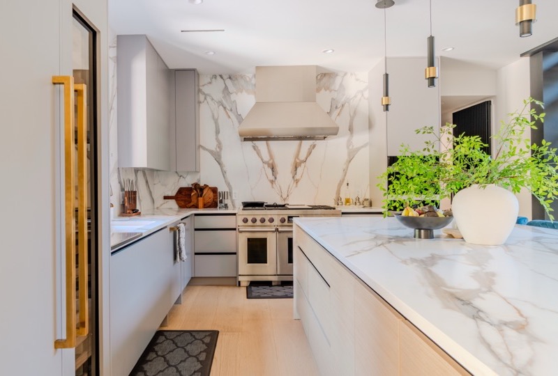 Luxury kitchen with marble waterfall island, custom cabinetry, and brass pendant lighting — premium add-ons including virtual staging and cinematic walkthroughs